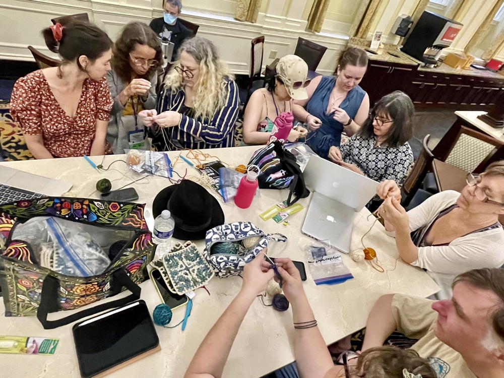 People working on crochet together at a large table